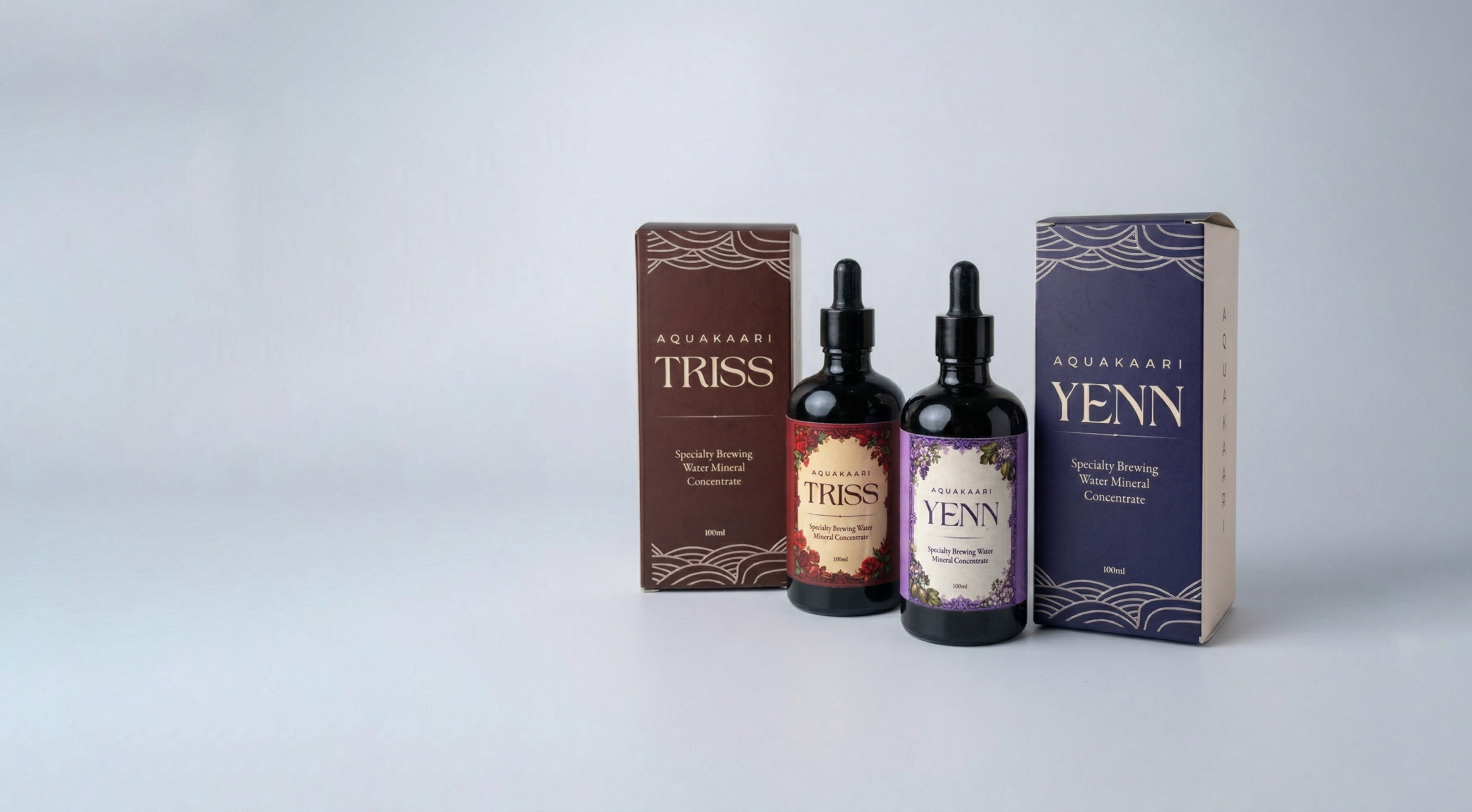 Two bottles of Aquakaari Triss and Yenn with their packaging on a white background
